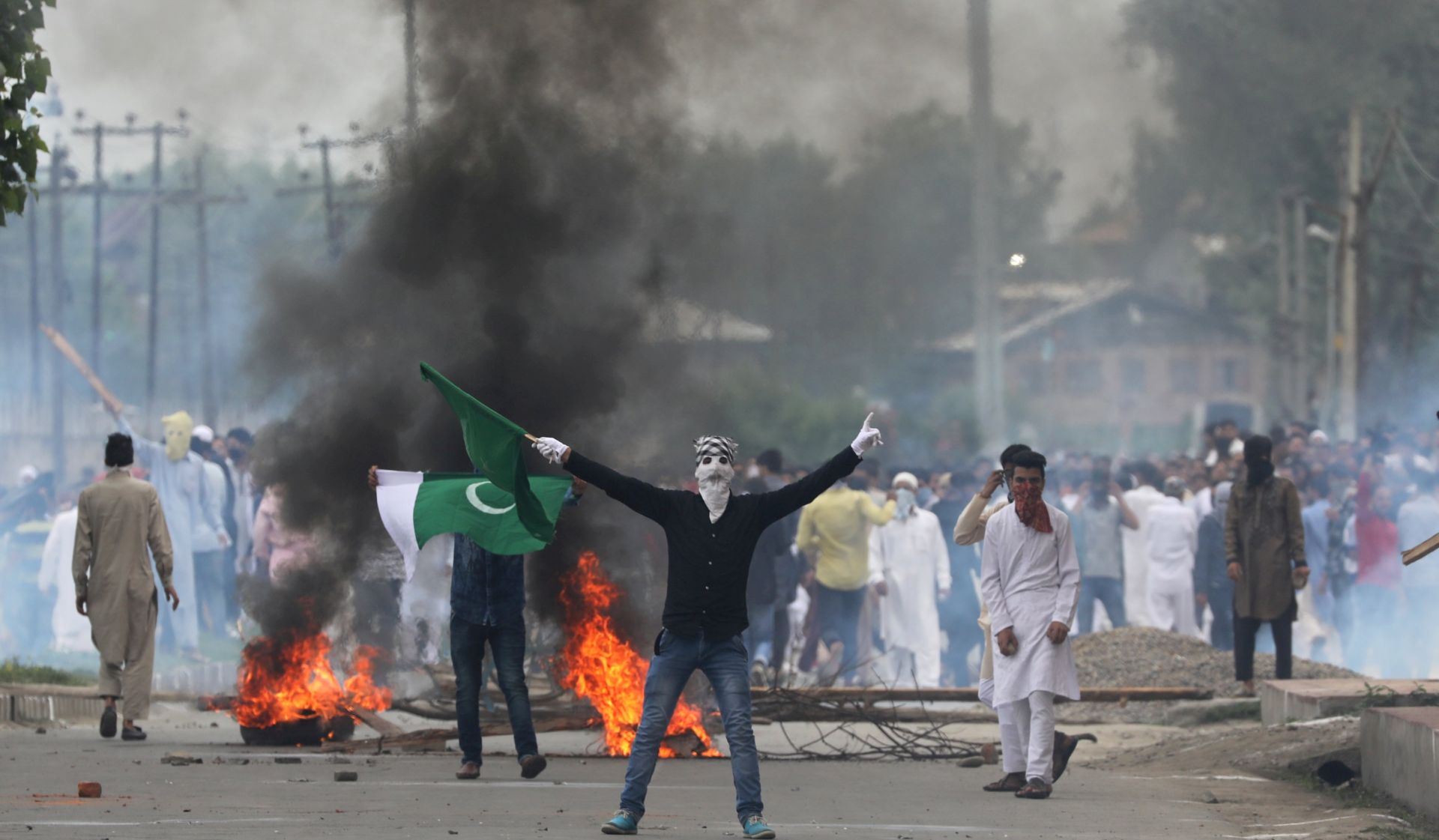 epa06050986 Kashmiri Muslim protesters throw stones and waive flags during clashes with police and paramilitary officers in the downtown area of Srinagar, the summer capital of Indian Kashmir, 26 June 2017. Police fired tear gas canisters, pellets and rubber bullets to disperse the Kashmiri Muslim protesters who were protesting after the culmination of Eid-al-Fitr congregational prayers.  EPA/FAROOQ KHAN