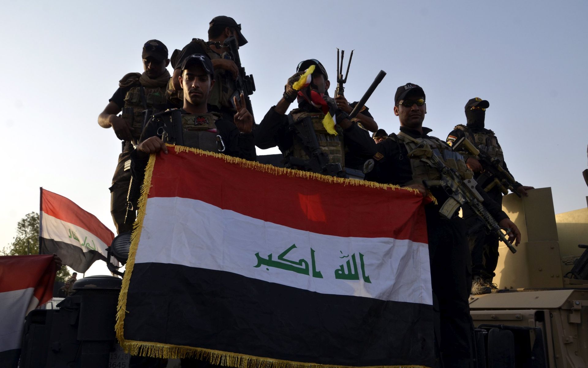 epa06080137 Iraqi soldiers hold up the Iraqi national flag in central Mosul, northern Iraq on 11 July 2017.  Iraqi Prime Minister Haider al-Abadi declared Mosul's liberation from Islamic state group Control (IS) after eight months of fierce fighting by Iraqi forces and a US-led coalition to oust the militants from their final stronghold in the country.  EPA/STR