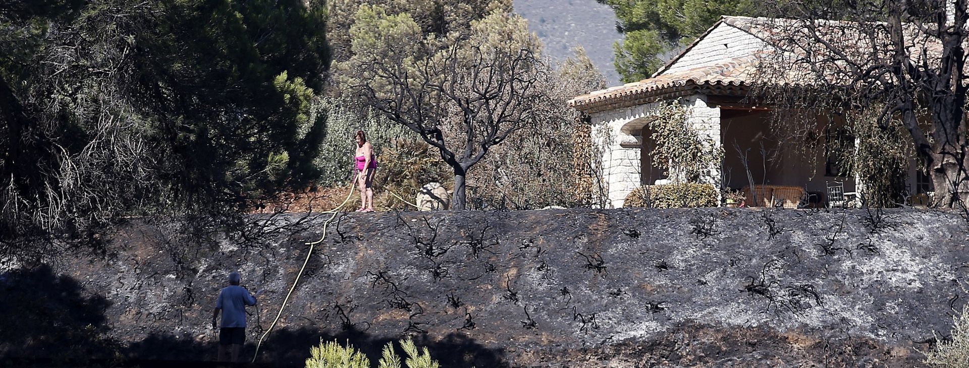 epa06108970 Local resident view the damages after a forest fire in Carros near Nice, southern France, 25 July 2017.  EPA/SEBASTIEN NOGIER
