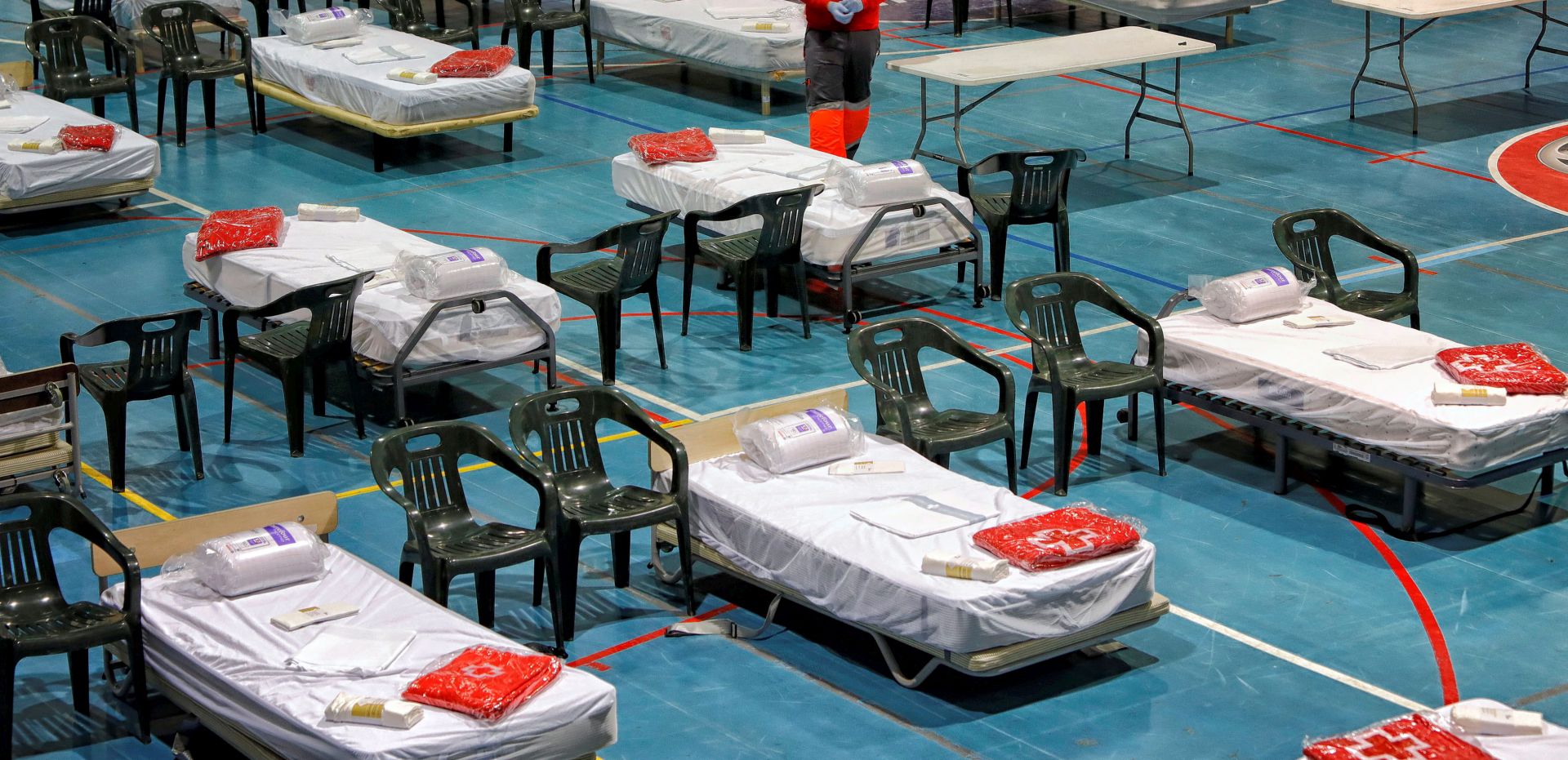 epa08337396 A member of the Spanish Red Cross sets up beds in a temporary hospital at Les Comas in Igualada, Barcelona, Spain, 01 April 2020. Countries around the world are taking increased measures to stem the widespread of the SARS-CoV-2 coronavirus which causes the COVID-19 disease.  EPA/Susanna Saez