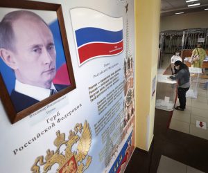 epa08519559 A woman votes during the main day of a nationwide vote on amendments to the Russian Constitution next to a portrait of Russian President Vladimir Putin at a polling station in Moscow, Russia, 01 July 2020.  EPA/MAXIM SHIPENKOV