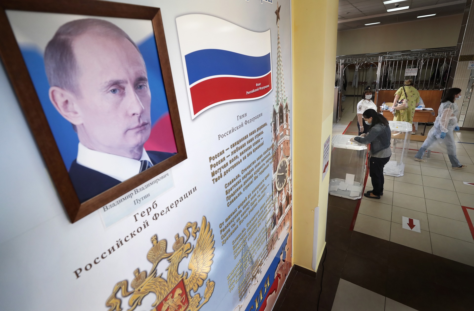 epa08519559 A woman votes during the main day of a nationwide vote on amendments to the Russian Constitution next to a portrait of Russian President Vladimir Putin at a polling station in Moscow, Russia, 01 July 2020.  EPA/MAXIM SHIPENKOV