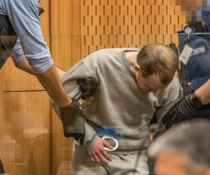 epa08626151 Guards handle Brenton Tarrant (C) during day three sentencing at the High Court in Christchurch, New Zealand, 26 August 2020. Australian white supremacist Brenton Tarrant will be sentenced for terrorism, 51 murders and 40 attempted murders, for his attack on two mosques in Christchurch in 2019.  EPA/JOHN KIRK-ANDERSON / POOL AUSTRALIA AND NEW ZEALAND OUT  
IMAGE PIXELATED AT SOURCE