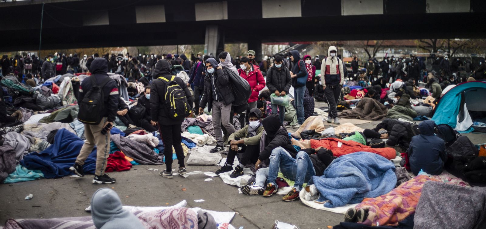 epa08824931 Thousands of migrants wait to be evacuated by French police forces at a makeshift migrant camp set along the A1 freeway in Saint-Denis, north of Paris, France, early 17 November 2020. French forces dismantled a migrant camp in Paris's northern suburb early in the morning and evacuated about 2,500 refugees.  EPA/YOAN VALAT *** Local Caption *** 55607528