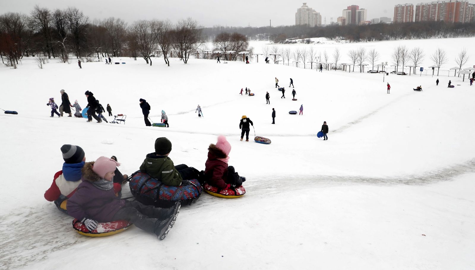 epa08920877 Children slide down a hill during the Christmas holidays in Moscow, Russia, 05 January 2021. Russians are preparing to celebrate the Christmas which is observed on 07 January according to the Russian Orthodox Julian calendar, 13 days after Christmas on 25 December on the Gregorian calender.  EPA/MAXIM SHIPENKOV