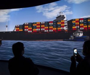 epa09104782 Reporters stand in front of a screen displaying a simulation of the pulling of Ever Given container ship in the Suez Canal, demonstrated during a press conference at the Maritime Training and Simulation Centre of the Suez Canal Authority in Ismailia, Egypt, 29 March 2021. The Suez Canal Authority announced on 29 March that the large container ship, which ran aground in the Suez Canal on 23 March, was partly refloated after responding to the pulling maneuvers and the back of the ship is now 102 meters away from the bank of the canal.  EPA/Mohamed Hossam