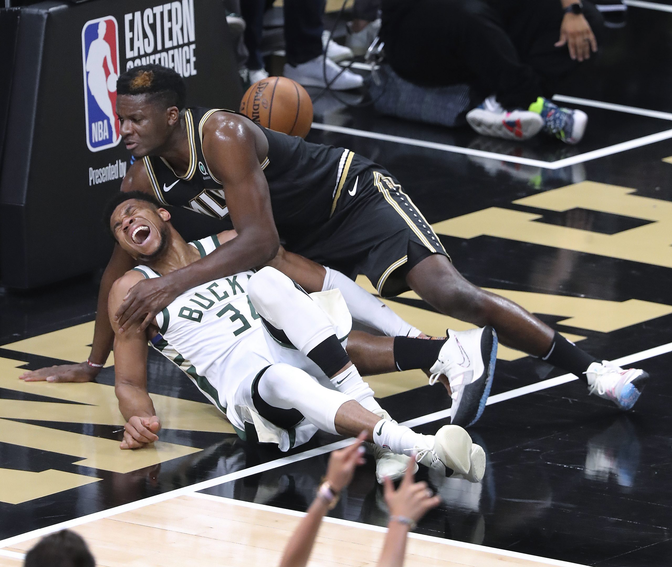 Atlanta Hawks center Clint Capela, top, and Milwaukee Bucks forward Giannis Antetokounmpo fall to the court during the third quarter in Game 4 of the Eastern Conference finals in the NBA basketball playoffs Tuesday, June 29, 2021, in Atlanta. Antetokounmpo left the game. (Curtis Compton/Atlanta Journal-Constitution via AP)