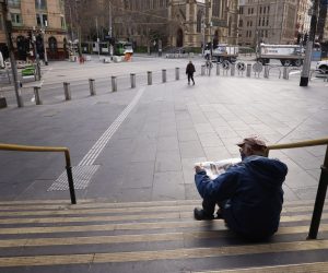 epa09408982 A man reads the newspaper on the steps of Flinders Street Station in Melbourne, Victoria, Australia, 11 August 2021. Regional Victoria's lockdown is over but people in Melbourne are still days from finding out when theirs will end.  EPA/DANIEL POCKETT AUSTRALIA AND NEW ZEALAND OUT