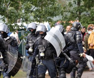 epa09388778 Riot Police officers and migrants at the tent camp in the Rudninkai training ground, Lithuania, 02 August 2021. Heavy rain on 02 August has triggered migrants that are detained at Rudninkai training ground, a former airbase which has recently been converted into a migrant detention center, to protest against the living conditions at the overcrowded tent camp.  EPA/TOMS KALNINS