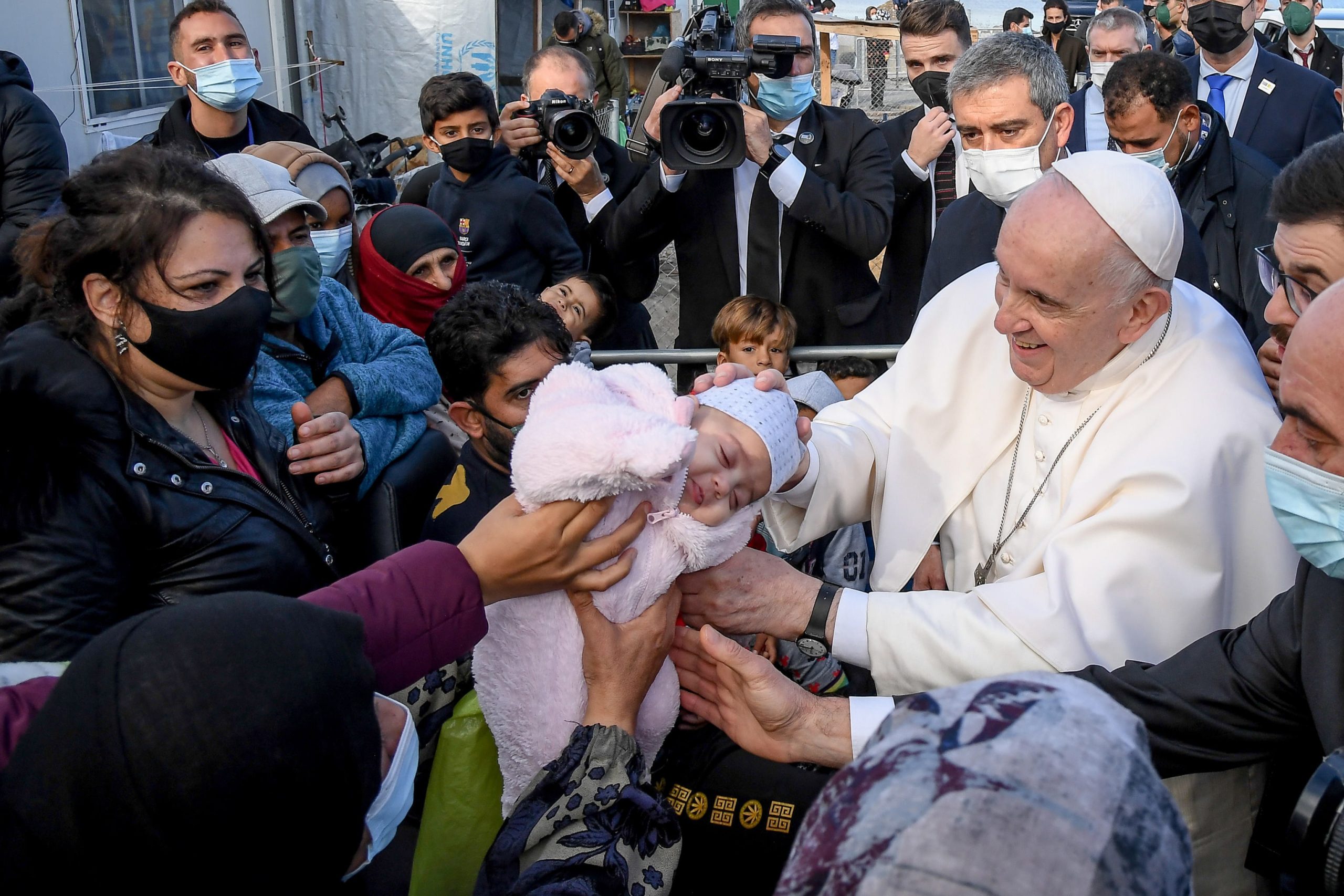 epa09623089 Pope Francis blesses a baby child at the Reception and Identification Centre (RIC) in Mytilene on the island of Lesbos, Greece, 05 December 2021. Pope Francis returned to the island of Lesbos, the migration flashpoint he first visited in 2016, to plead for better treatment of refugees as attitudes towards migrants harden across Europe.  EPA/ALESSANDRO DI MEO