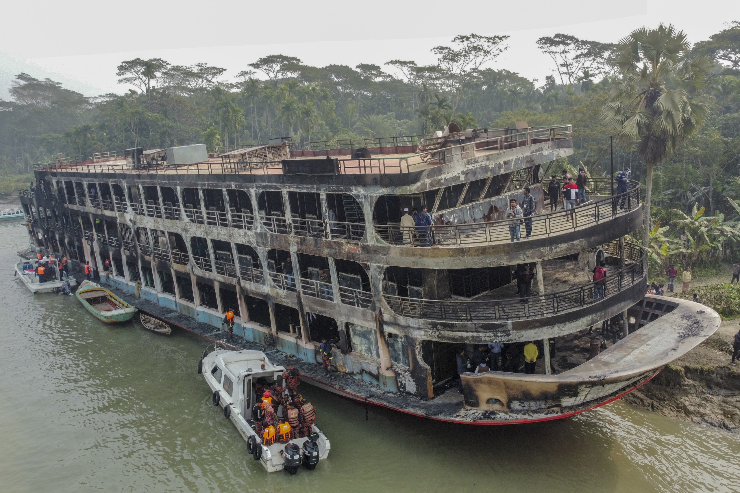 epa09655641 Firefighters and coast guards shift body bags of victims after a passenger ferry caught fire near the southern rural town of Jhalakathi,  south of Dhaka in Bangladesh, 24 December 2021. At least 36 people died after a ferry caught fire on the Sugandha River in southern Bangladesh near Jhalakathi Sadar upazila early Friday in Bangladesh, according to Police and Fire service.  EPA/STR