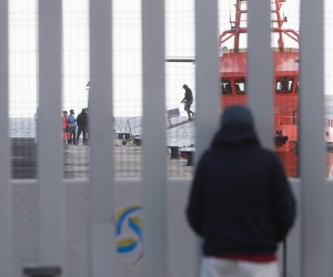 epa09710755 A person watches the arrival of migrants at Puerto del Rosario harbor in Fuerteventura, Canary Islands, Spain, 26 January 2022. A group of 32 migrants was rescued by a Sea Rescue crew while traveling in a small boat close to Lanzarote island and then transferred to the neighboring island of Fuerteventura, as Lanzarote's facilities are overcrowded. Some 409 migrants were rescued in the last 24 hours in the Canary Islands.  EPA/Carlos de Saa