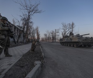 epa09851747 Russian serviceman guards on the street as infantry armoured vehicle drives in downtown Volnovakha, Ukraine, 26 March 2022. Troops of the self-proclaimed Donetsk People's Republic with Russian support entered Volnovakha, a small town near Donetsk. Donetsk People's Republic official said that the housing stock of the city of Volnovakha was destroyed by 85 percent, the city would have to be rebuilt. On 24 February Russian troops had entered Ukrainian territory in what the Russian president declared a 'special military operation', resulting in fighting and destruction in the country, a huge flow of refugees, and multiple sanctions against Russia.  EPA/SERGEI ILNITSKY