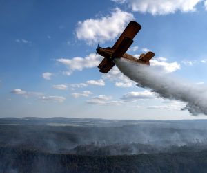 epa10094345 A plane drops water as firefighters operate on a forest fire near the village of Hrensko, Czeck Republic, 27 July 2022. The fire has been raging for 3 days, affecting the border area between the Czech Republic and Germany.  EPA/RAY BASELEY