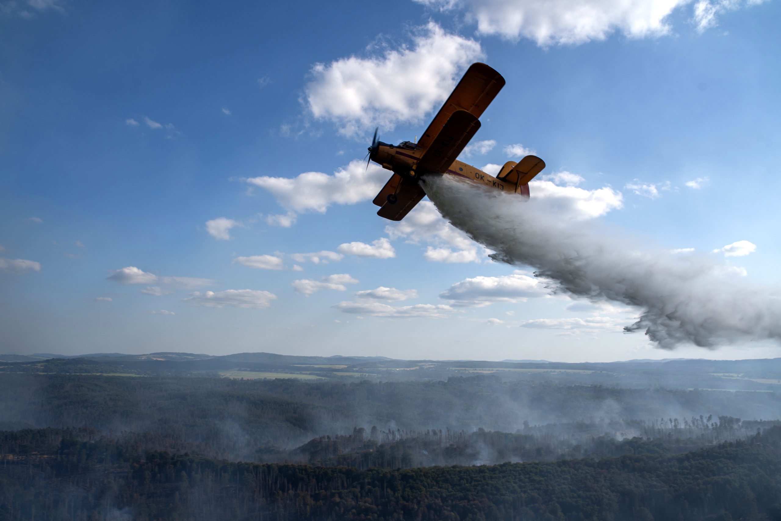 epa10094345 A plane drops water as firefighters operate on a forest fire near the village of Hrensko, Czeck Republic, 27 July 2022. The fire has been raging for 3 days, affecting the border area between the Czech Republic and Germany.  EPA/RAY BASELEY