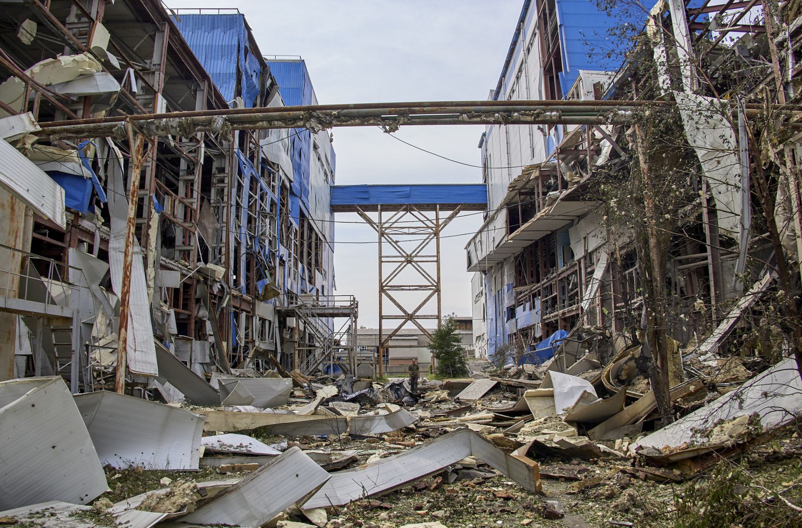 epa10101564 A man walks past a damaged factory building after a rocket hit in the small city of Merefa in the Kharkiv area, Ukraine, 01 August 2022. Kharkiv and surrounding areas have been the target of heavy shelling since February 2022, when Russian troops entered Ukraine starting a conflict that has provoked destruction and a humanitarian crisis.  EPA/SERGEY KOZLOV