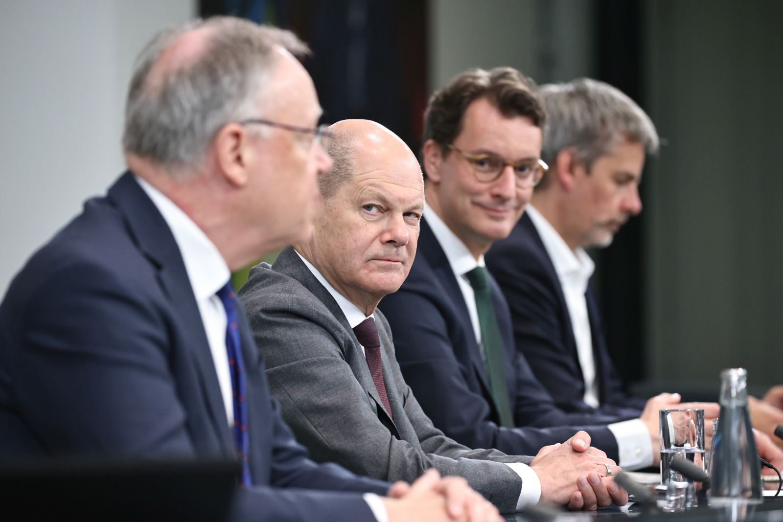 epa10619856 German Chancellor Olaf Scholz (2-L) looks towards Lower Saxony State Premier Stephan Weil (L) next to North Rhine-Westphalia State Premier Hendrik Wuest (3-L) and the spokesman of the German government Steffen Hebestreit (R) during a press conference following a meeting of heads of government of the federal states and the German chancellor at the chancellery in Berlin, Germany, 10 May 2023. The Federal Chancellor and the heads of government of the federal states are expected to discuss current issues in refugee policy.  EPA/CLEMENS BILAN