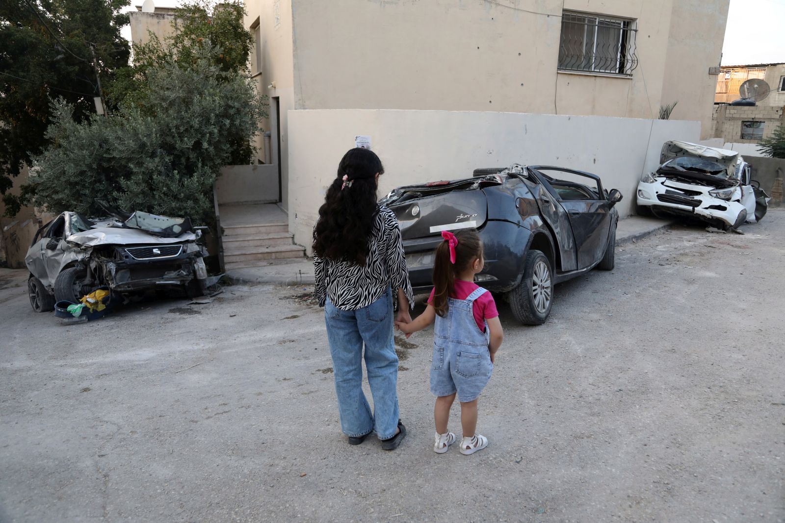 epa10732869 Palestinian children look at damaged cars at Jenin refugee camp, after an Israeli army raid in the West Bank city of Jenin, 07 July 2023. The Israeli army announced on 05 July the withdrawal of its soldiers from Jenin, after launching a large-scale operation two days earlier. According to the Palestinian Health Ministry, 12 Palestinians were killed and dozens of others wounded in the raid. The Israeli Defense Forces (IDF) also announced the death of 'a non-commissioned officer in combat service' during the raid.  EPA/ALAA BADARNEH