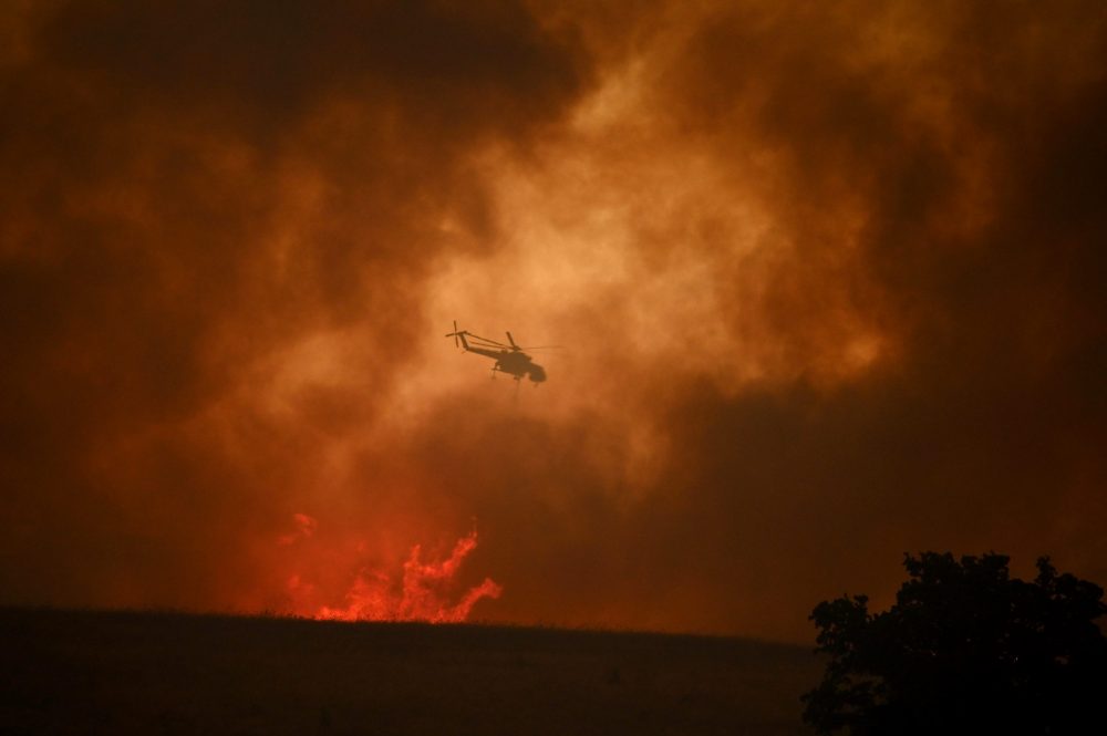 epa10812681 A firefighting helicopter drops water to extinguish a wildfire in Avantas village, near the city of Alexandroupolis, Thrace, northern Greece, 21 August 2023. The wildfire that broke out early on 19 August in a forest in the Melia area of Alexandroupolis has spread rapidly due to the strong winds blowing in the area and is raging uncontrolled. The major wildfire in Alexandroupolis continues with unabated intensity for the third consecutive day. According to the Fire Department, the fire is difficult to be contained due to the strong winds in the area.  EPA/DIMITRIS ALEXOUDIS