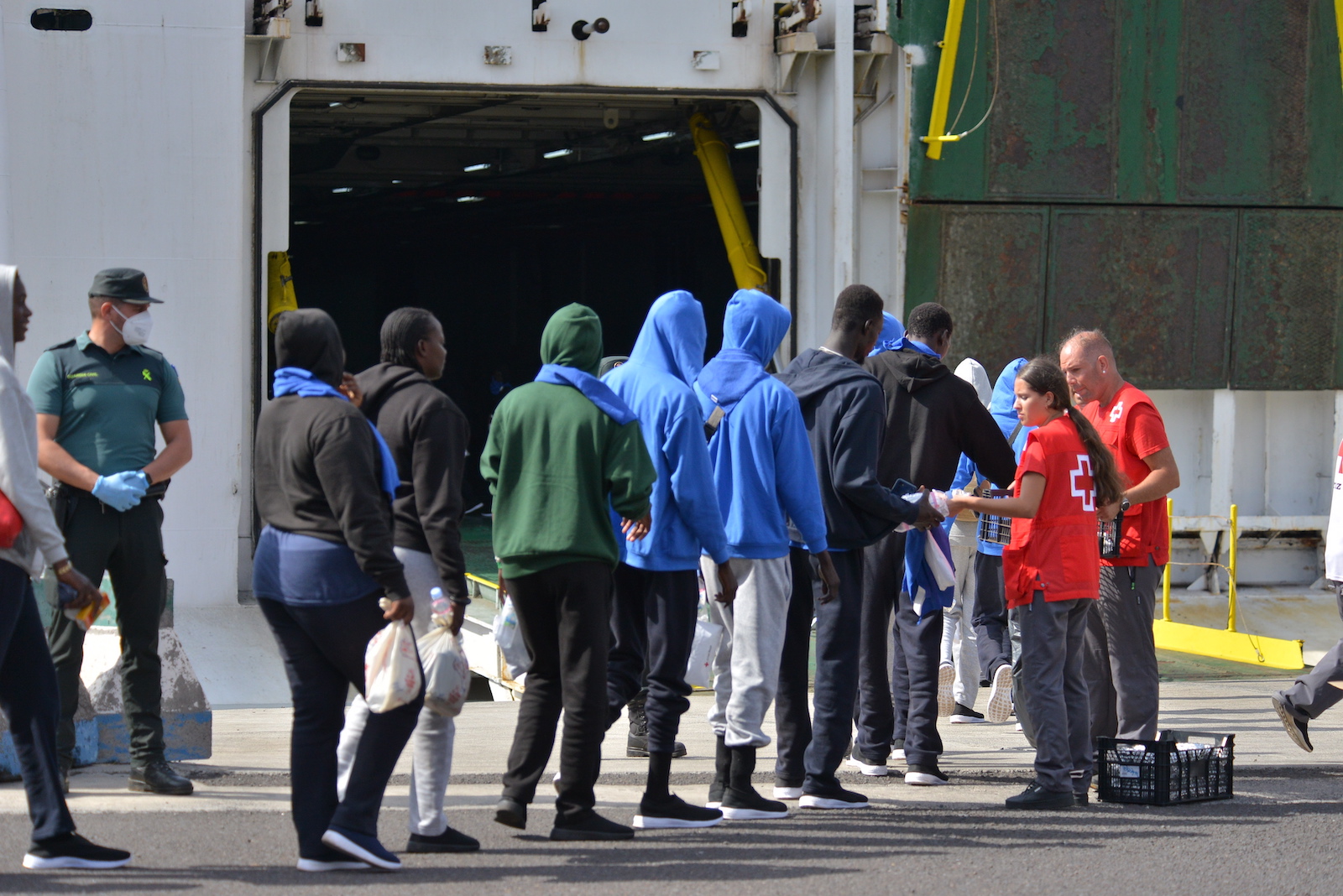 epa10854677 Red Cross members take care of migrants before they are transferred to Tenerife on board a ferry of Spanish ferry services company 'Naviera Armas' from Valverde's port in El Hierro island, Canary Islands, Spain, 11 September 2023. A total of 313 migrants will be transfered to Tenerife after reaching the Spanish coasts on board of small boats.  EPA/GELMERT FINOL