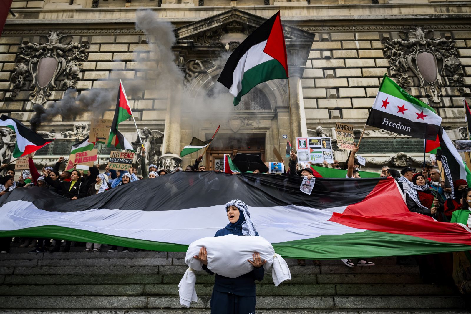 epa10927717 Protesters hold placards and Palestinian flags during a rally in support of the Palestinian people in Lausanne, Switzerland, 19 October 2023. Thousands of Israelis and Palestinians have died since the militant group Hamas launched an unprecedented attack on Israel from the Gaza Strip on 07 October 2023, leading to Israeli retaliation strikes on the Palestinian enclave.  EPA/JEAN-CHRISTOPHE BOTT