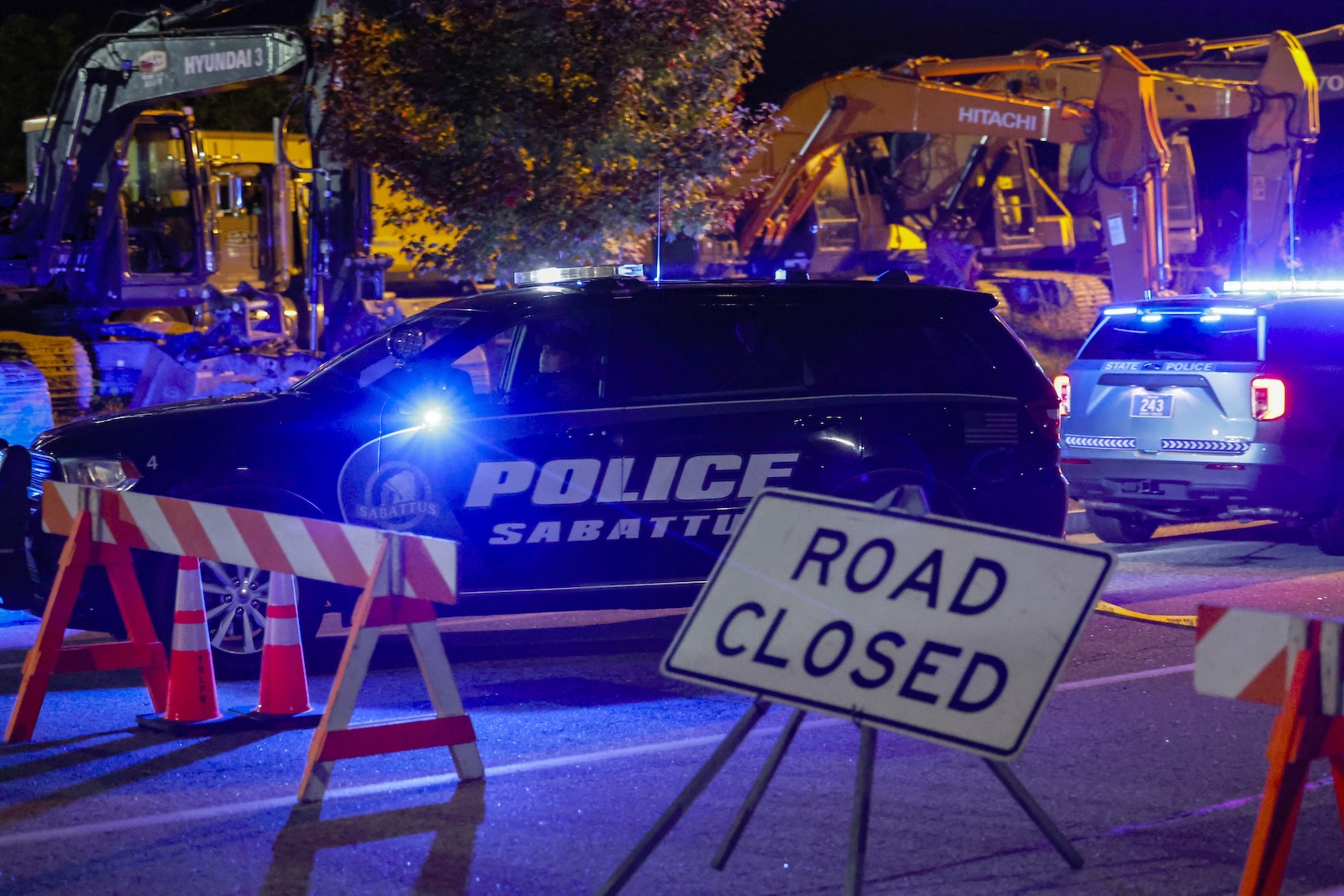 epa10939780 A police car drives past a road block sign on the road leading to Schemengees bar where a man reportedly opened fire killing and injuring numerous people in Lewiston, Maine, USA, 25 October 2023. Early reports indicate as many as 20 people have been killed, and dozens injured. Police are still searching for the suspect.  EPA/CJ GUNTHER