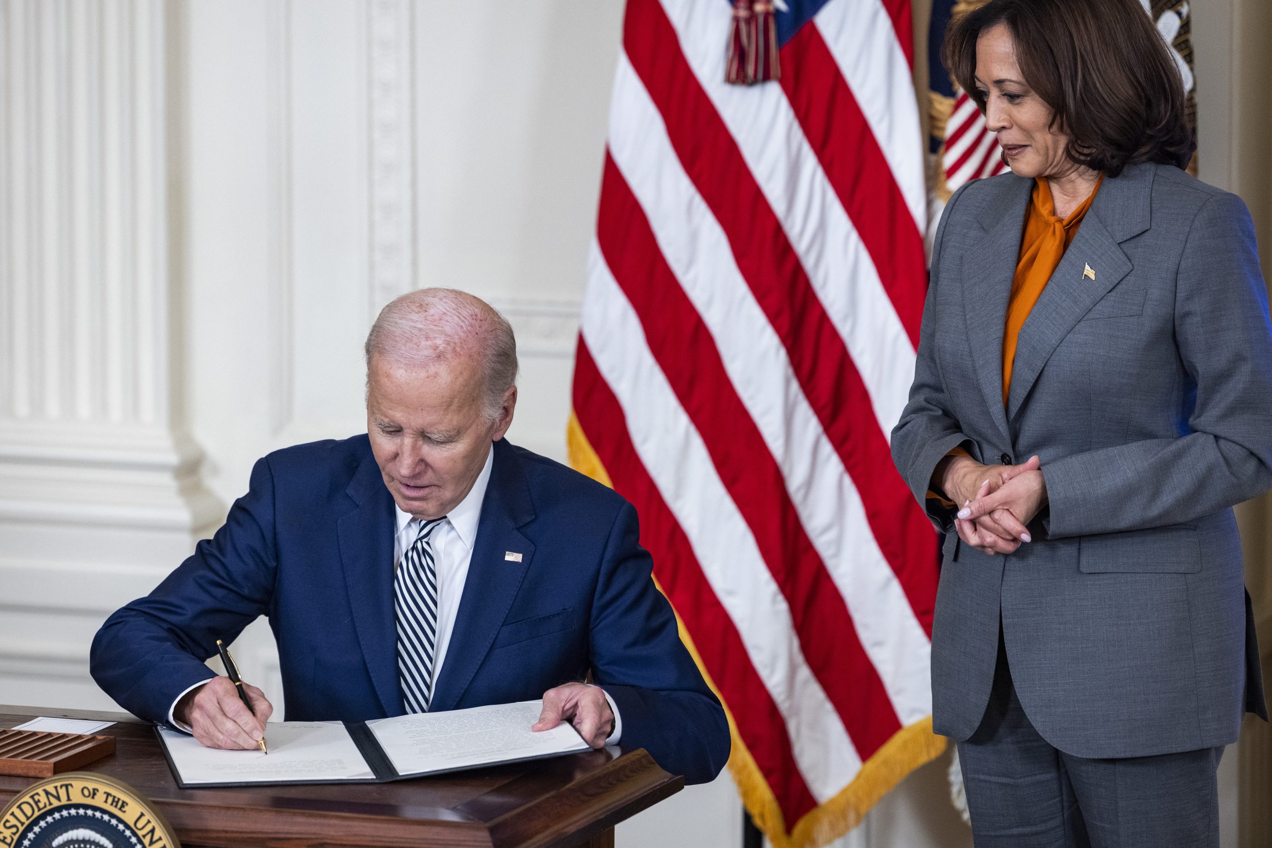 epa10949418 US President Joe Biden (L), alongside Vice President Kamala Harris (R), signs an executive order to regulate artificial intelligence (A.I.) in the East Room of the White House in Washington, DC, USA, 30 October 2023. Biden's order is the first federal regulation of the developing industry.  EPA/JIM LO SCALZO