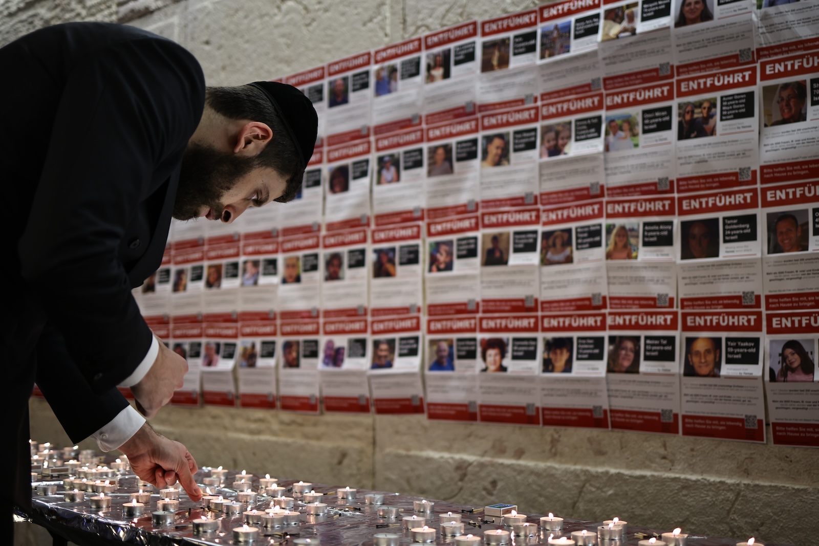 epa10956305 A participant lights a candle in front of kidnapped person's fliers at the Synagogue Muenstersche Strasse in Berlin, Germany, 03 November 2023. The Jewish Community Chabad Berlin held a candle-lighting ceremony for the hostages held by Hamas. At least 242 hostages are being held in Gaza according to the Israel Defense Forces (IDF) and the Palestinian health authority, since Hamas militants launched an attack against Israel from the Gaza Strip on 07 October 2023.  EPA/CLEMENS BILAN