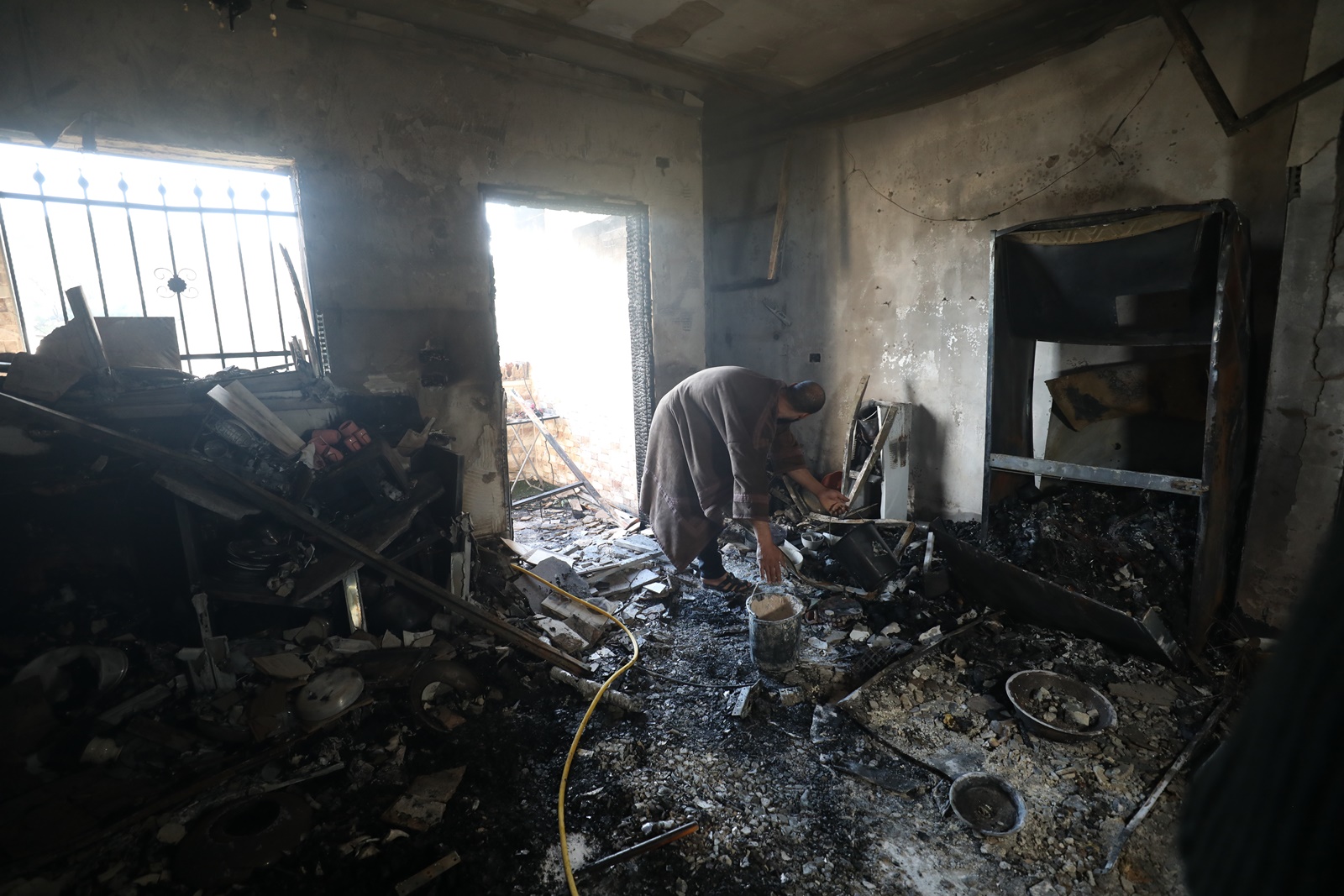 epa11026176 Palestinians inspect damage at a burned house as Israeli forces conduct a raid for a second day at Jenin refugee camp near the West Bank city of Jenin, 13 December 2023. According to the Palestinian Health ministry, seven Palestinians were killed in Jenin during an Israeli military raid on 12 December. Thousands of Israelis and Palestinians have died since the militant group Hamas launched an unprecedented attack on Israel from the Gaza Strip on 07 October, and the Israeli operations in Gaza and the West Bank which followed it.  EPA/ALAA BADARNEH