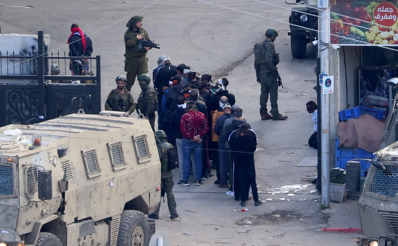 epa11055283 Palestinians stand in line after their arrest by Israeli troops during a military operation at Nur Shams refugee camp near Tulkarem city, West Bank, 03 January 2023. According to the Palestinian Health Ministry, six people were wounded following an ongoing Isareli army operation at Nur Shams refugee camp, which started on 02 January.  EPA/ALAA BADARNEH