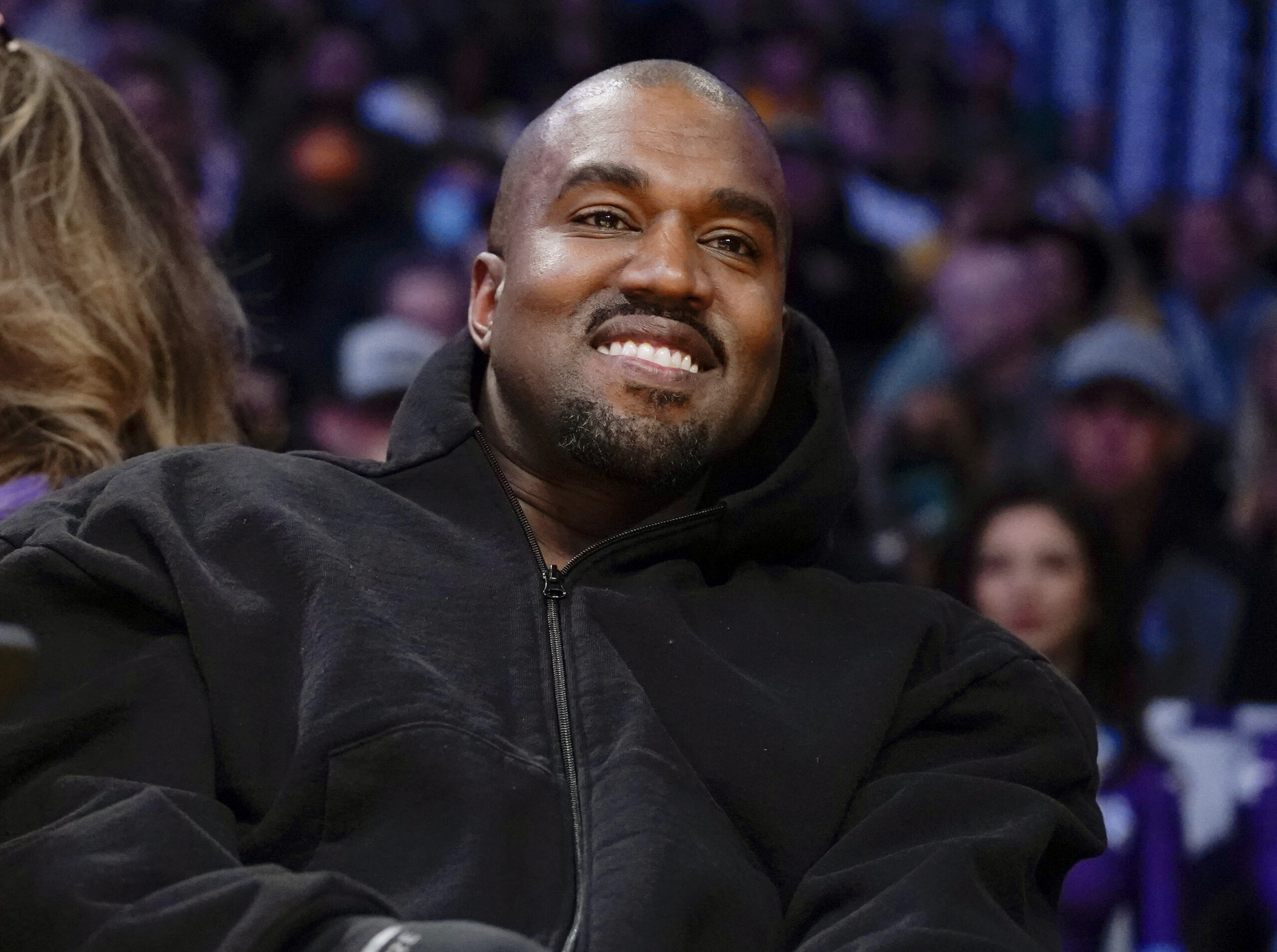 FILE - Kanye West, known as Ye, watches the first half of an NBA basketball game between the Washington Wizards and the Los Angeles Lakers, on March 11, 2022, in Los Angeles. Adidas said Wednesday March 13, 2024 that it's donated or is planning to give away more than $150 million to groups fighting antisemitism and other forms of hate from the sales of Yeezy shoes last year after it severed ties with Ye, the rapper formerly known as Kanye West. (AP Photo/Ashley Landis, File)