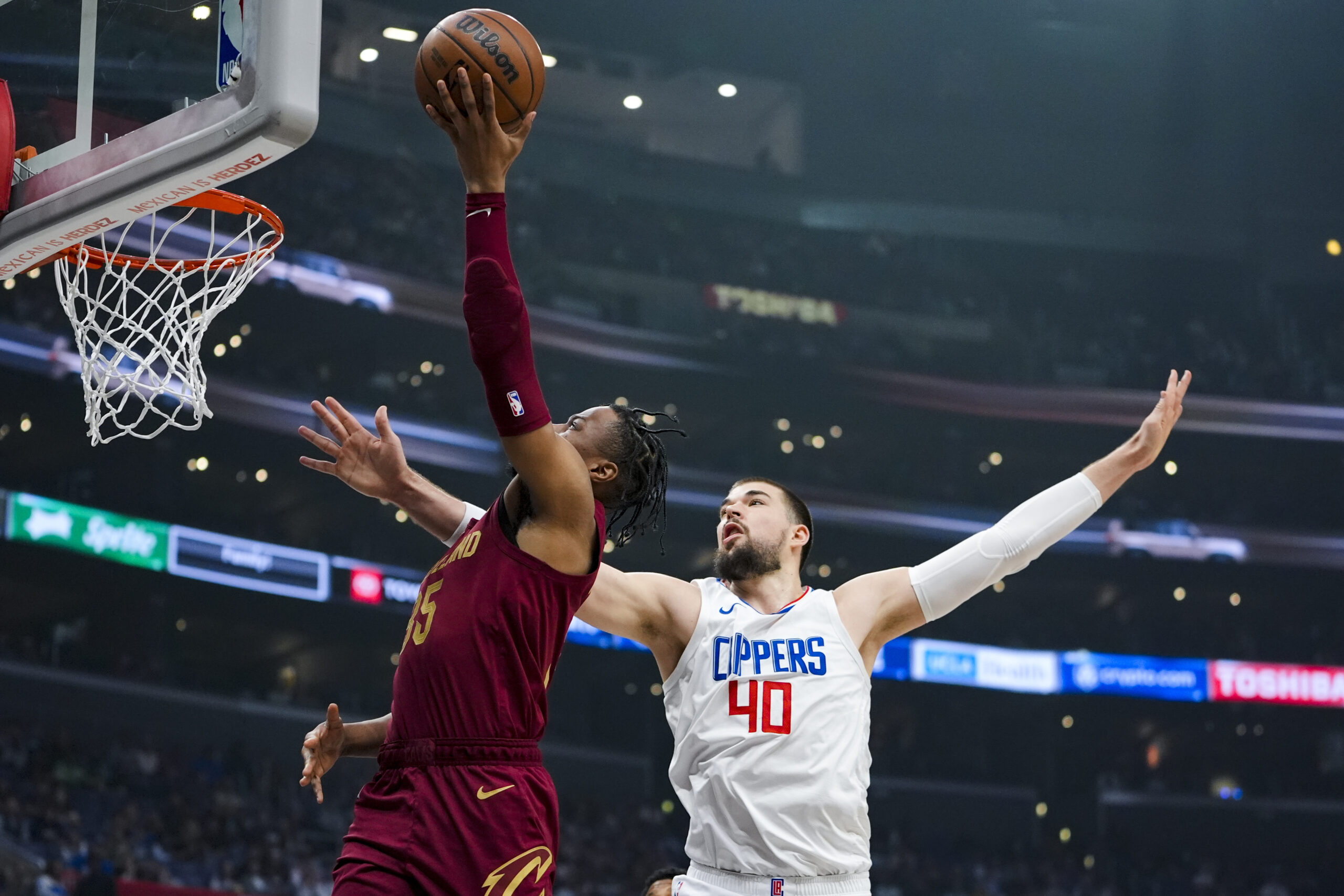 Cleveland Cavaliers forward Isaac Okoro, left, drives past Los Angeles Clippers center Ivica Zubac during the first half of an NBA basketball game, Sunday, April 7, 2024, in Los Angeles. (AP Photo/Ryan Sun)