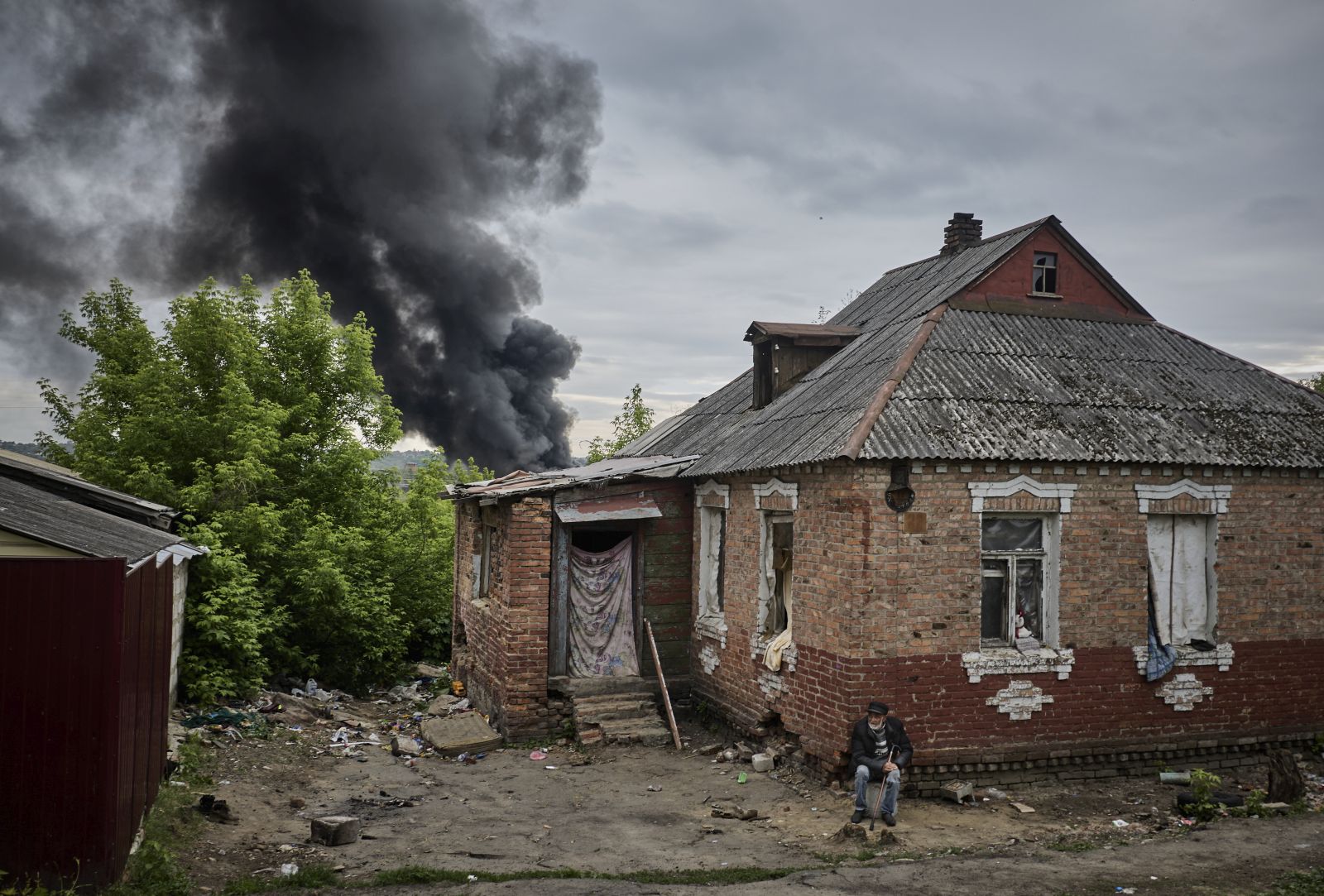 epa11348680 A local man sits near his damaged home as smoke rises after shelling, on the outskirts of Kharkiv, Ukraine, 17 May 2024, amid the Russian invasion. More than 9,000 residents from settlements in areas of the Kharkiv region bordering Russia have been evacuated as hostilities intensified, the head of the Kharkiv Military Administration Oleg Synegubov said on 17 May. The evacuations follow a cross-border offensive by Russian forces, who claimed the capture of several villages in the region. Russian troops entered Ukrainian territory on 24 February 2022, starting a conflict that has provoked destruction and a humanitarian crisis.  EPA/SERGEY KOZLOV