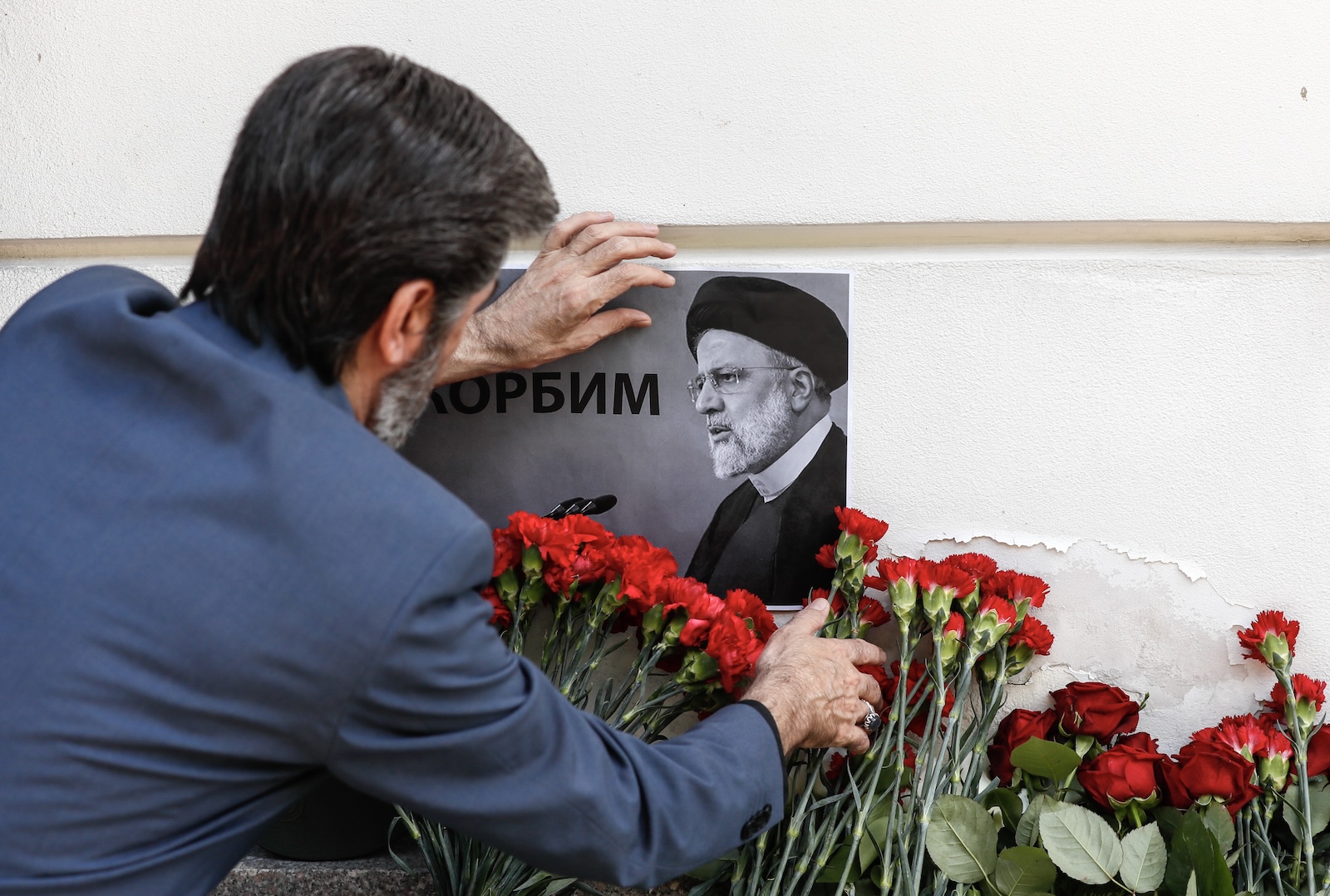 epa11355321 A man places a portrait of the late Iranian President Ebrahim Raisi next to flowers laid outside the Iranian embassy, following the deaths of Iran's president Raisi and Foreign Minister Amir-Abdollahian, in Moscow, Russia, 20 May 2024. According to Iranian state media, President Raisi, Foreign Minister Hossein Amir-Abdollahian and several others were killed in a helicopter crash in the mountainous Varzaghan area on 19 May, during their return to Tehran, after an inauguration ceremony of the joint Iran-Azerbaijan constructed Qiz-Qalasi dam at the Aras river. Iran's first Vice President Mohammad Mokhber was appointed as the country's interim president following the death of Raisi, Iranian supreme leader Ayatollah Ali Khamenei announced in a condolence message on 20 May 2024.  EPA/YURI KOCHETKOV