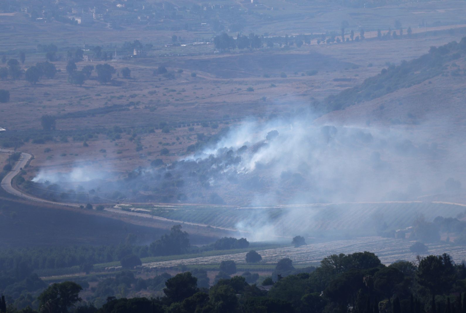 epa11428497 Smoke rises as a result of strikes from Lebanon, near Kipputz Snir, northern Israel, with the Lebanese village of Al Khiamin the background, Israel, 21 June 2024. According to the Israeli army, several rocket launches were identified crossing from Lebanon into northern Israel. No injuries were reported, the Israely army said.  EPA/ATEF SAFADI