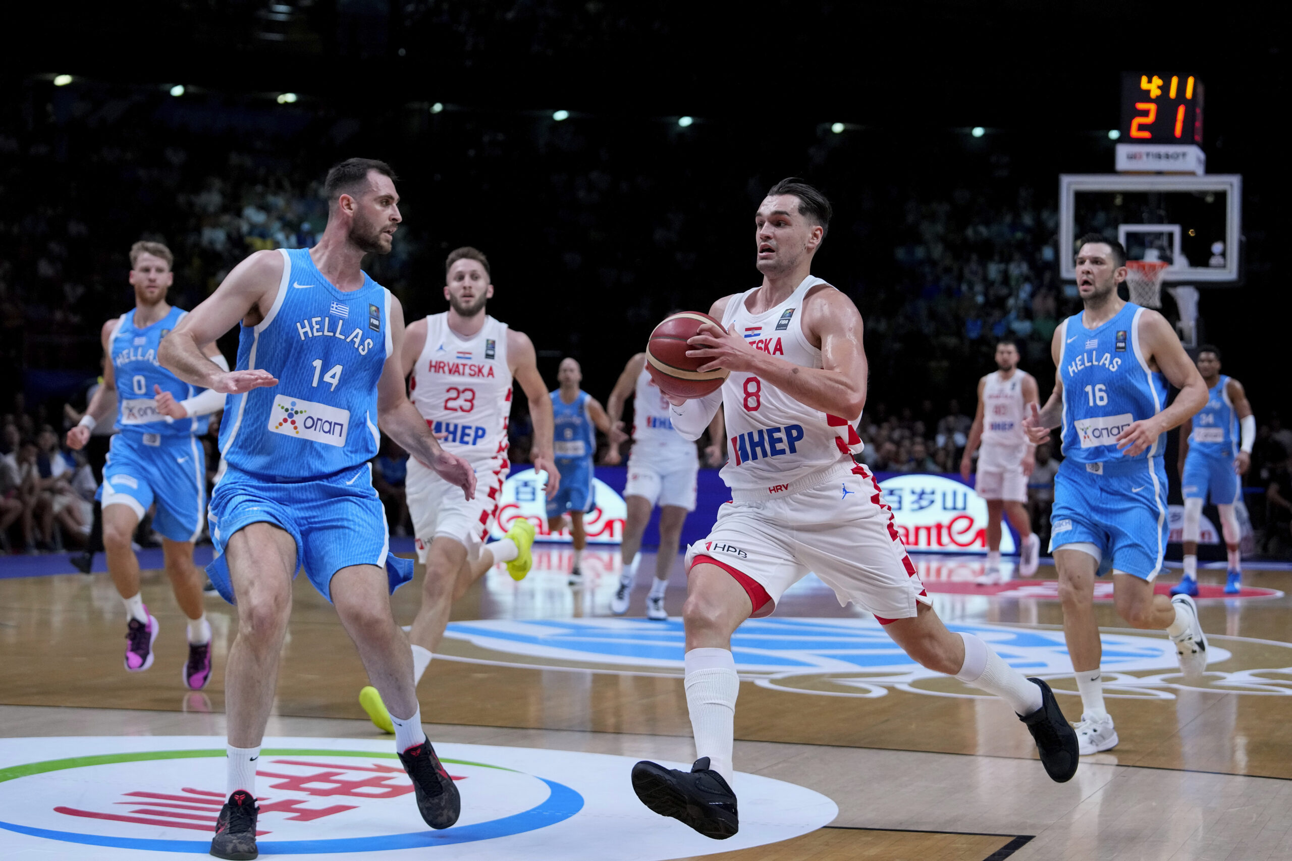 Croatia's Mario Hezonja, right, advances with the ball against Greece's Georgios Papagiannis, during a FIBA Olympic Qualifying basketball final, at the Peace and Friendship stadium, at Athens' port city of Piraeus, Sunday, July 7, 2024. (AP Photo/Petros Giannakouris)