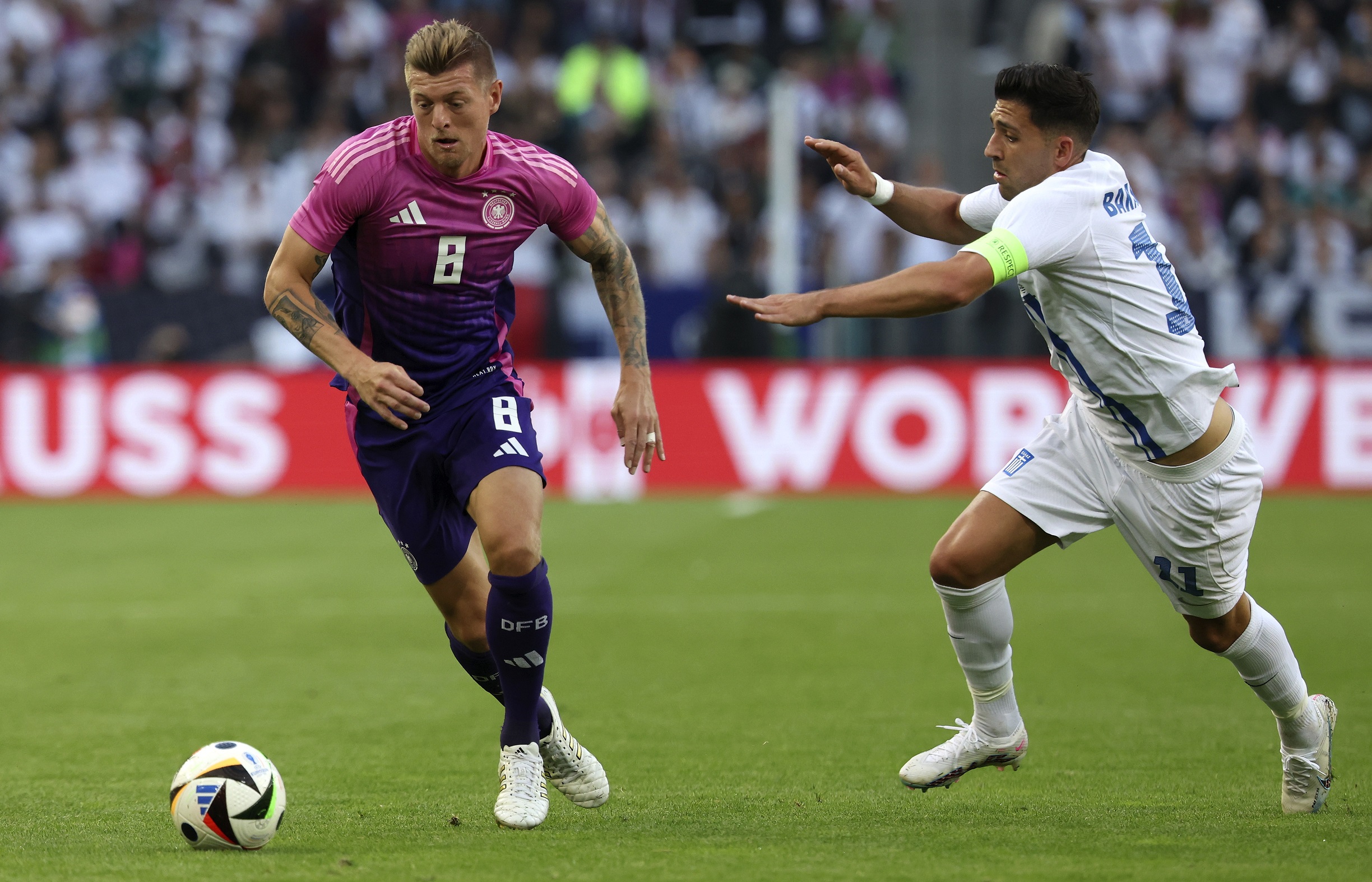 epa11396498 Toni Kroos of Germany (L) in action against Anastasios Bakasetas of Greece (R) during the international friendly soccer match between Germany and Greece in Moenchengladbach, Germany, 07 June 2024.  EPA/CHRISTOPHER NEUNDORF