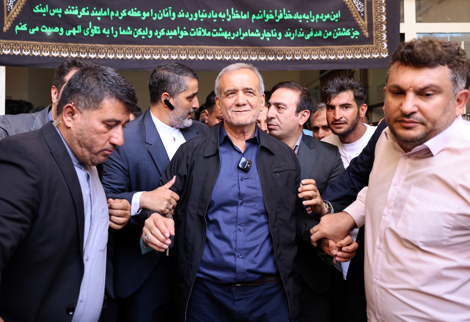 epa11461407 (FILE) - Iranian reformist presidential candidate Masoud Pezeshkian (C) is escorted after casting his vote at a polling station during the presidential election in Ghaleh Hasan Khan, Iran, 05 July 2024 (reissued 06 July 2024). According to a statement issued by the Ministry of Interior, Masoud Pezeshkian won the presidential runoff election, held in the wake of the death of late Iranian President Ebrahim Raisi, whom died in a hellicopter crash. Iran held the second round of its presidential election on 05 July 2024.  EPA/STR