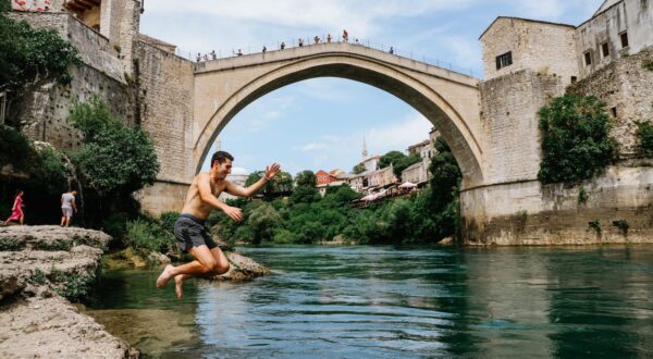 05.06.2022. Mostar - Stari grad pun turista koji vrijedno nagradjuju hrabre skakace za skok sa Starog mosta. Oni hrabriji spas od vrucina traze u hladnoj Neretvi. Photo: Denis Kapetanovic/PIXSELL