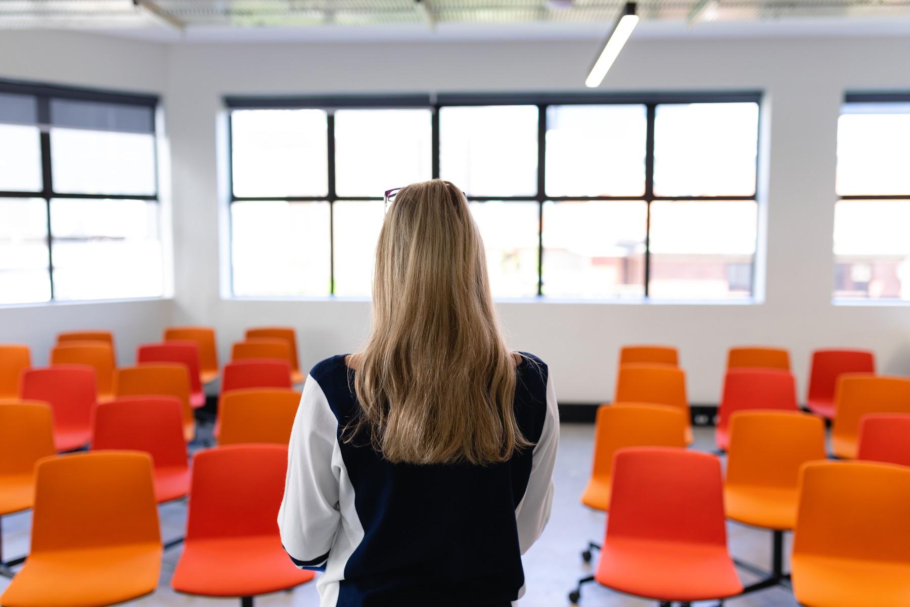 Rear view of a Caucasian woman with long blond hair, wearing smart clothes, standing in an empty modern meeting room, training her speech for conference.,Image: 532618463, License: Rights-managed, Restrictions: , Model Release: yes, Credit line: Wavebreak Media LTD / Wavebreak / Profimedia