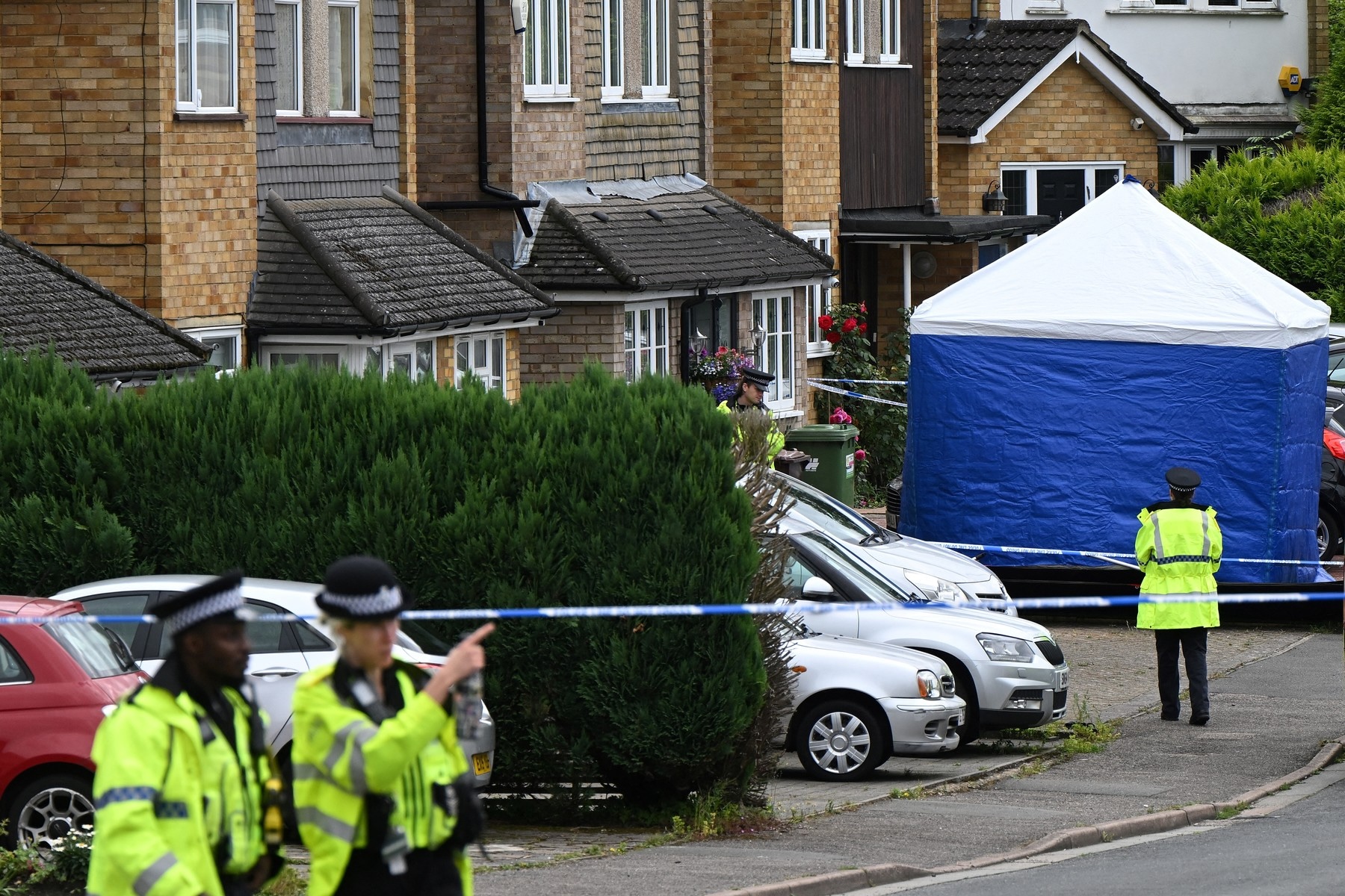 Police officers stand guard by a forensic team tent at Ashley Close in Bushey in the borough of Hertfordshire, north of London, on July 10, 2024 after a triple "crossbow attack" murder. British police were searching for a suspect who may have a crossbow after the wife and two daughters of a BBC radio racing commentator were killed in what police believe was a "targeted" attack.,Image: 888779318, License: Rights-managed, Restrictions: , Model Release: no, Credit line: JUSTIN TALLIS / AFP / Profimedia