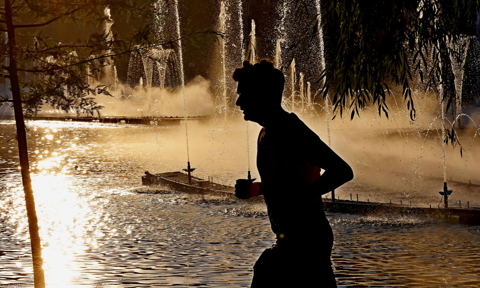 epa11480418 A man runs in the shade of the trees in Titan Park at sunset on a hot summer day with up to 42 Celsius degrees in Bucharest, Romania, 15 July 2024. On 15 July morning, the National Meteorological Administration declared the Red Code for extreme heat until 17 July 2024, as the temperature-humidity index (THI) is expected to exceed the critical value of 80.  EPA/ROBERT GHEMENT