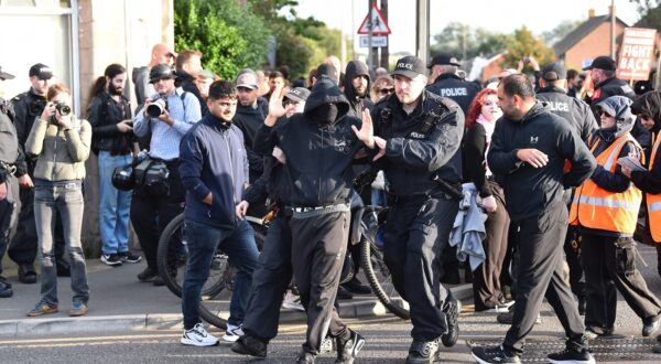 epa11534599 Police remove a protester who refused to remove their face mask outside the Merseyside Refugee Centre in Liverpool, Britain, 07 August 2024. Further far-right protests are expected throughout Britain on the 07 August 2024. Violent demonstrations have been held by members of far-right groups across Britain following a fatal stabbing attack in Southport, in which three children were killed and eight more seriously injured, along with two adults.  EPA/PETER POWELL