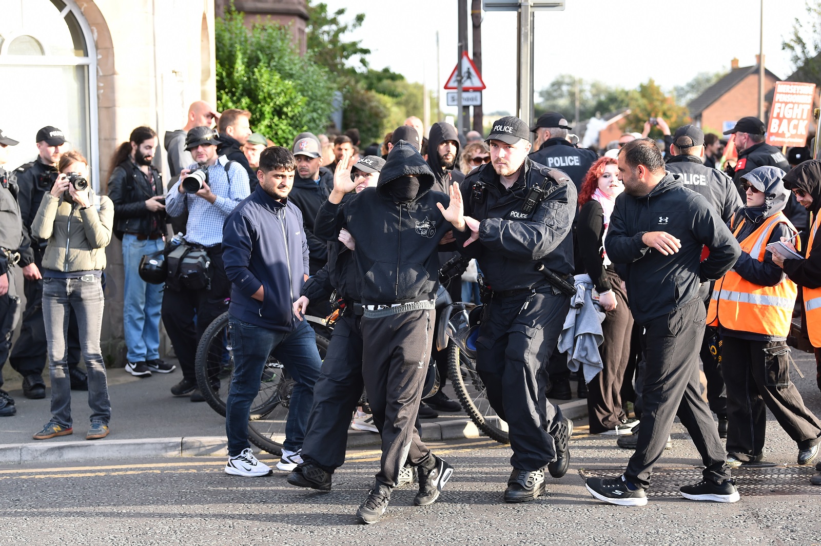 epa11534599 Police remove a protester who refused to remove their face mask outside the Merseyside Refugee Centre in Liverpool, Britain, 07 August 2024. Further far-right protests are expected throughout Britain on the 07 August 2024. Violent demonstrations have been held by members of far-right groups across Britain following a fatal stabbing attack in Southport, in which three children were killed and eight more seriously injured, along with two adults.  EPA/PETER POWELL