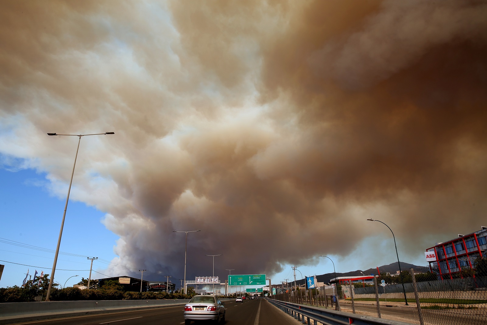 epa11545603 Thick smoke covers the National Highway in Athens from a wildfire that broke out in a farmland and forest area in Varnavas, Attica region, Greece, 11 August 2024. The fire brigade has deployed 165 firefighters, nine teams on foot, 30 vehicles, seven firefighting aircraft, and five helicopters to extinguish the flames. Varnavas residents have been instructed to evacuate the area via a message from the 112 emergency number.  EPA/ALEXANDROS BELTES