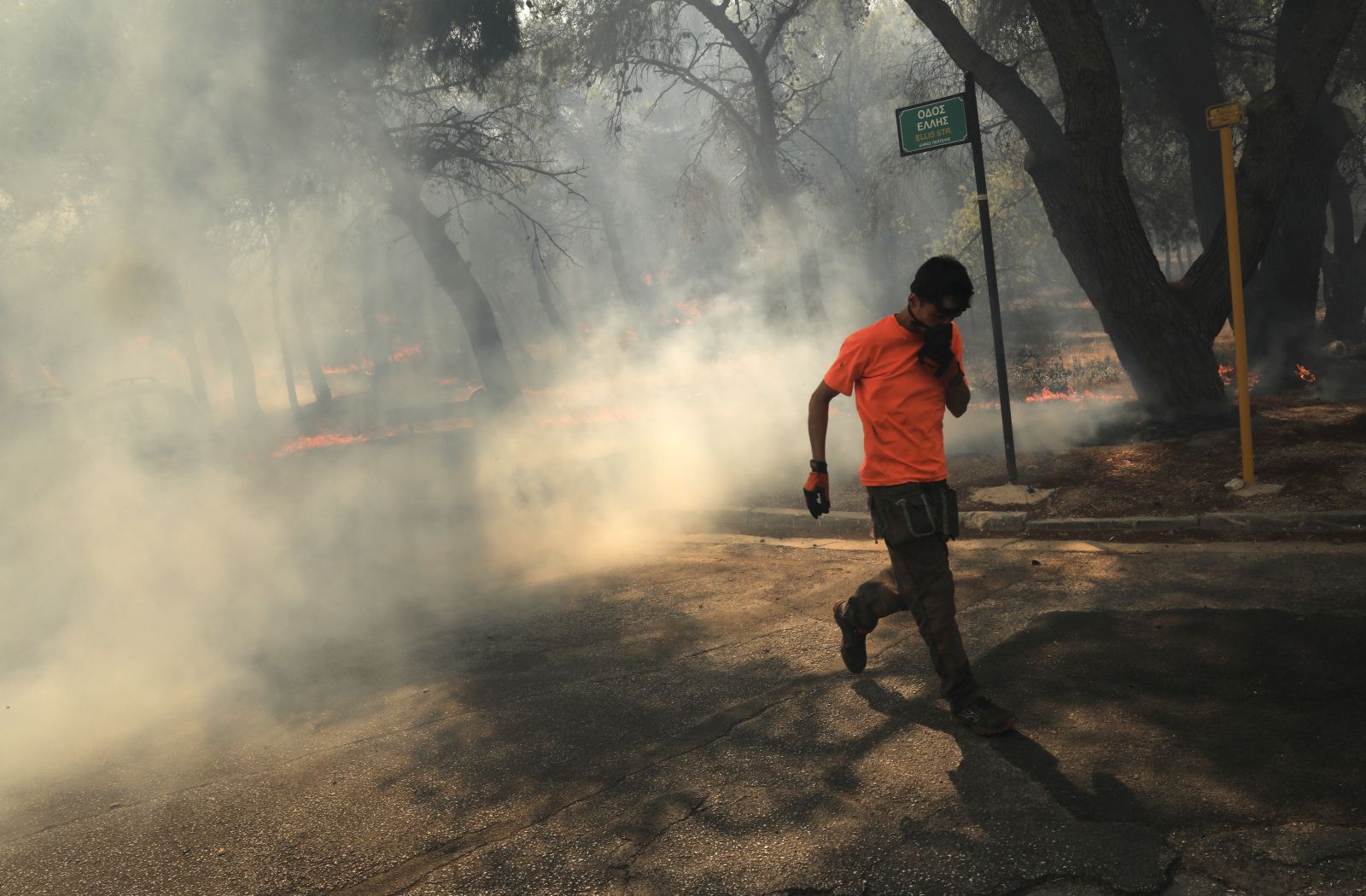 epa11546764 A man tries to protect himself from the smoke during a wildfire in Patima Halandri, a suburb of Athens, Greece, 12 August 2024. The wildfire that broke out in Varnavas on 11 August afternoon continued to rage in eastern Attica on 12 August, fanned and spread to a front extending more than 20 kilometers. According to the fire department, the fire-fighting effort is extremely difficult as the wind keeps changing direction, while the three main fronts of concern are in Grammatiko, Penteli and the Anatoli settlement in Nea Makri. A total of 685 firefighters, 27 of forest commando units, 190 fire engines, assisted by 17 water-dropping helicopters and 16 firefighting aircraft and volunteers with the contribution of all the civil protection entities are battling the blaze.  EPA/GEORGE VITSARAS