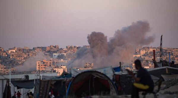 epa11547888 Smoke rises following an Israeli air strike as internally displaced Palestinians sit next to their tents in Khan Younis camp, southern Gaza Strip, 13 August 2024. More than 39,900 Palestinians and over 1,400 Israelis have been killed, according to the Palestinian Health Ministry and the Israel Defense Forces (IDF), since Hamas militants launched an attack against Israel from the Gaza Strip on 07 October 2023, and the Israeli operations in Gaza and the West Bank which followed it.  EPA/HAITHAM IMAD