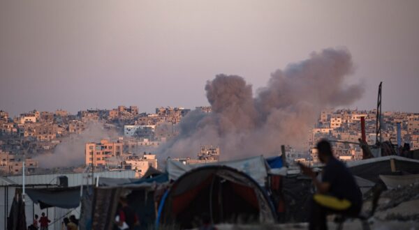 epa11547888 Smoke rises following an Israeli air strike as internally displaced Palestinians sit next to their tents in Khan Younis camp, southern Gaza Strip, 13 August 2024. More than 39,900 Palestinians and over 1,400 Israelis have been killed, according to the Palestinian Health Ministry and the Israel Defense Forces (IDF), since Hamas militants launched an attack against Israel from the Gaza Strip on 07 October 2023, and the Israeli operations in Gaza and the West Bank which followed it.  EPA/HAITHAM IMAD