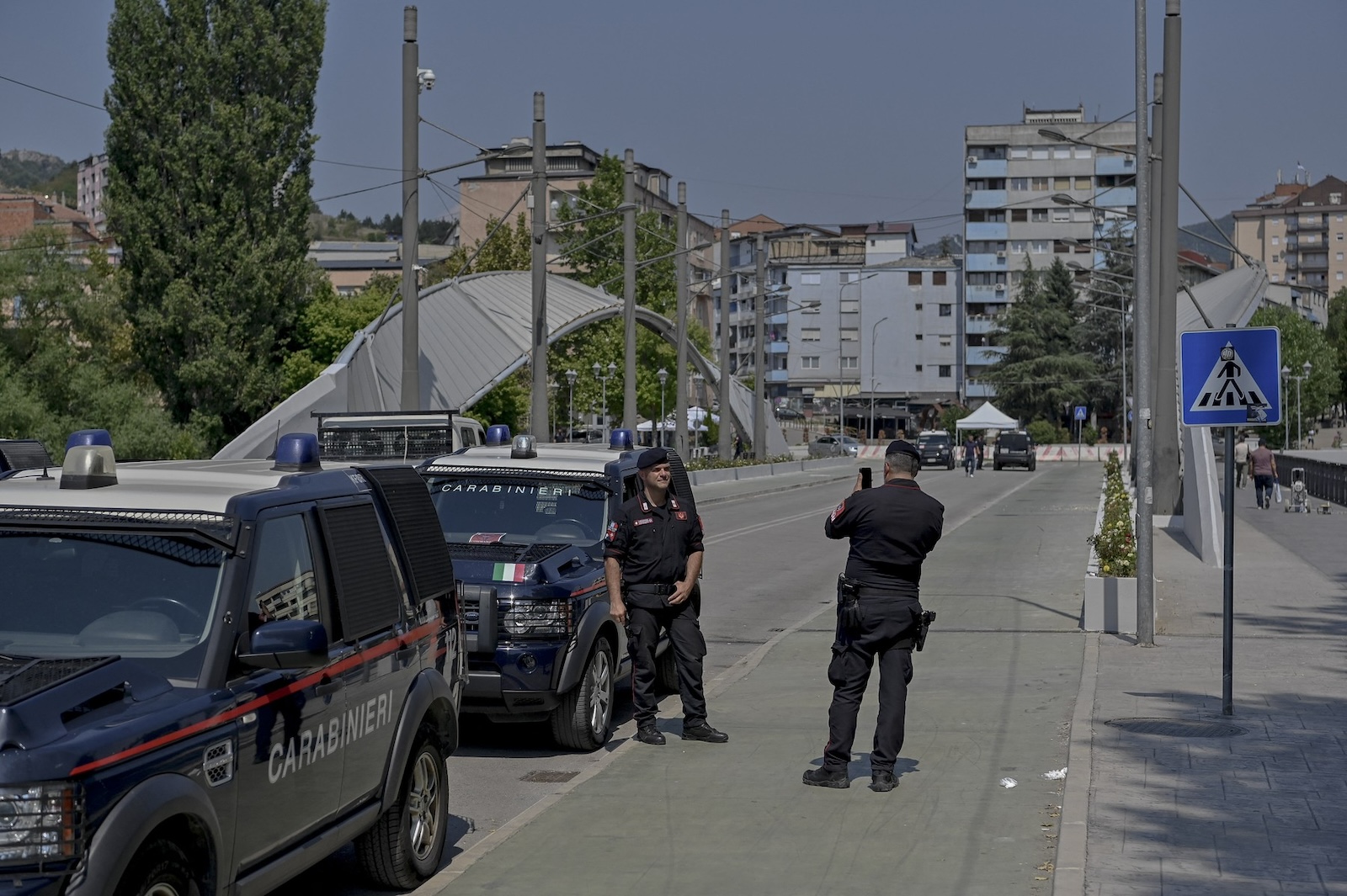 Italian Carabinieri members take pictures as they patrol at the Mitrovica bridge, that has long separated Serbs and ethnic Albanians in the restive northern area of Kosovo, in the divided city of Mitrovica on August 16, 2024. The bridge that divides the communities has been the scene of frequent clashes following the 1999 war between Serbian forces and Kosovo's ethnic Albanian majority, which left 13,000 dead and ended after a NATO bombing campaign led by Washington.,Image: 899159744, License: Rights-managed, Restrictions: , Model Release: no, Credit line: Armend NIMANI / AFP / Profimedia