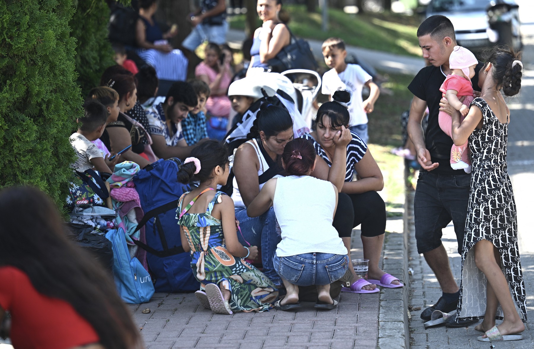 Ukrainian refugees from Transcarpathia sit on the pavement close to their former shelter in the village of Kocs, about 70 km north-west from the Hungarian capital Budapest, on August 21, 2024, after some 120 refugees were ousted from their guest house.
 Thousands of Ukrainian refugees face eviction from shelters in Hungary after a legislative change that came into effect on August 21, 2024 took away their access to state-subsidised accommodation. Most were Roma women and children from Transcarpathia in western Ukraine, where there is a large Hungarian community.,Image: 900398541, License: Rights-managed, Restrictions: , Model Release: no, Credit line: Attila KISBENEDEK / AFP / Profimedia